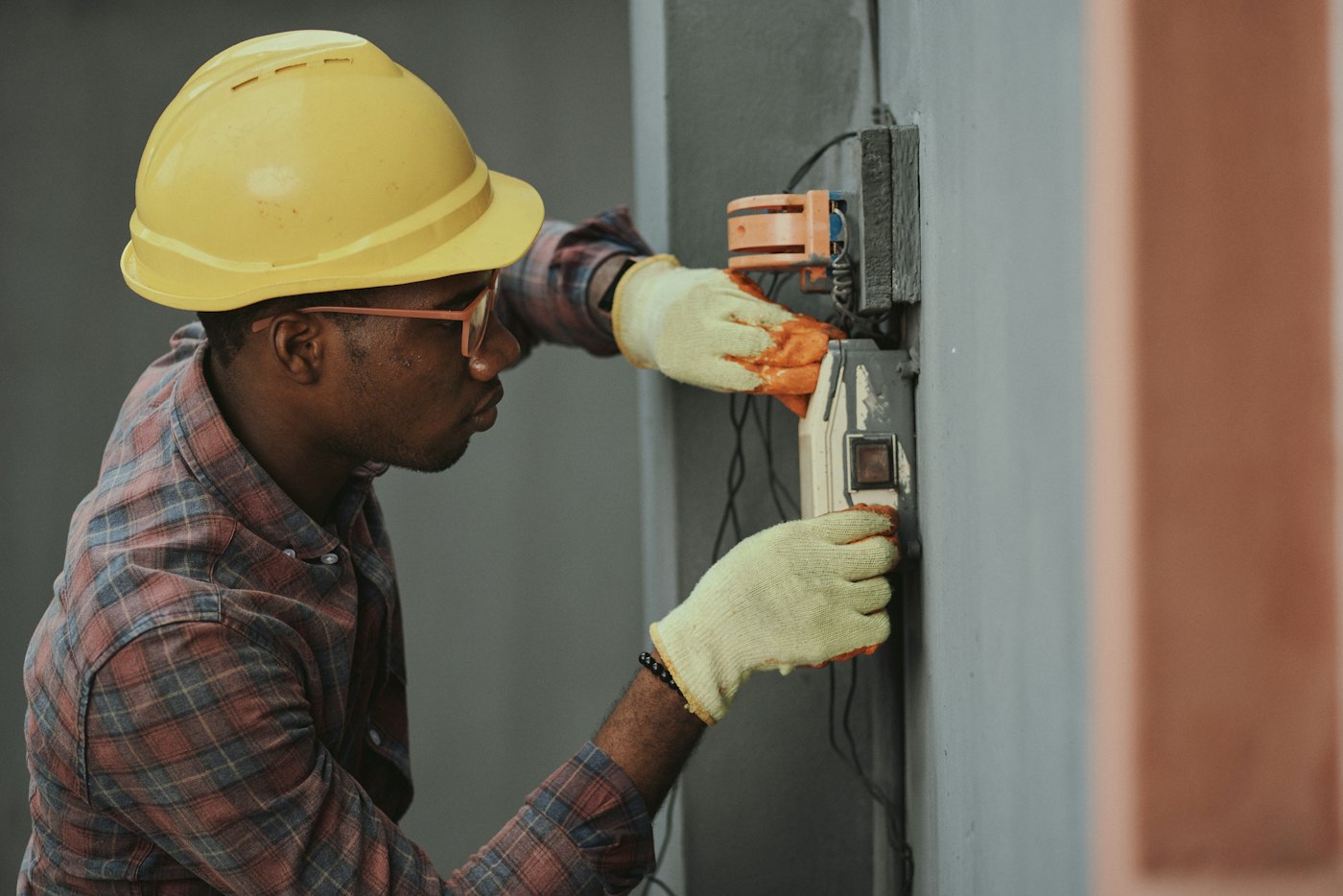 An electrician in a hard hat installing wiring