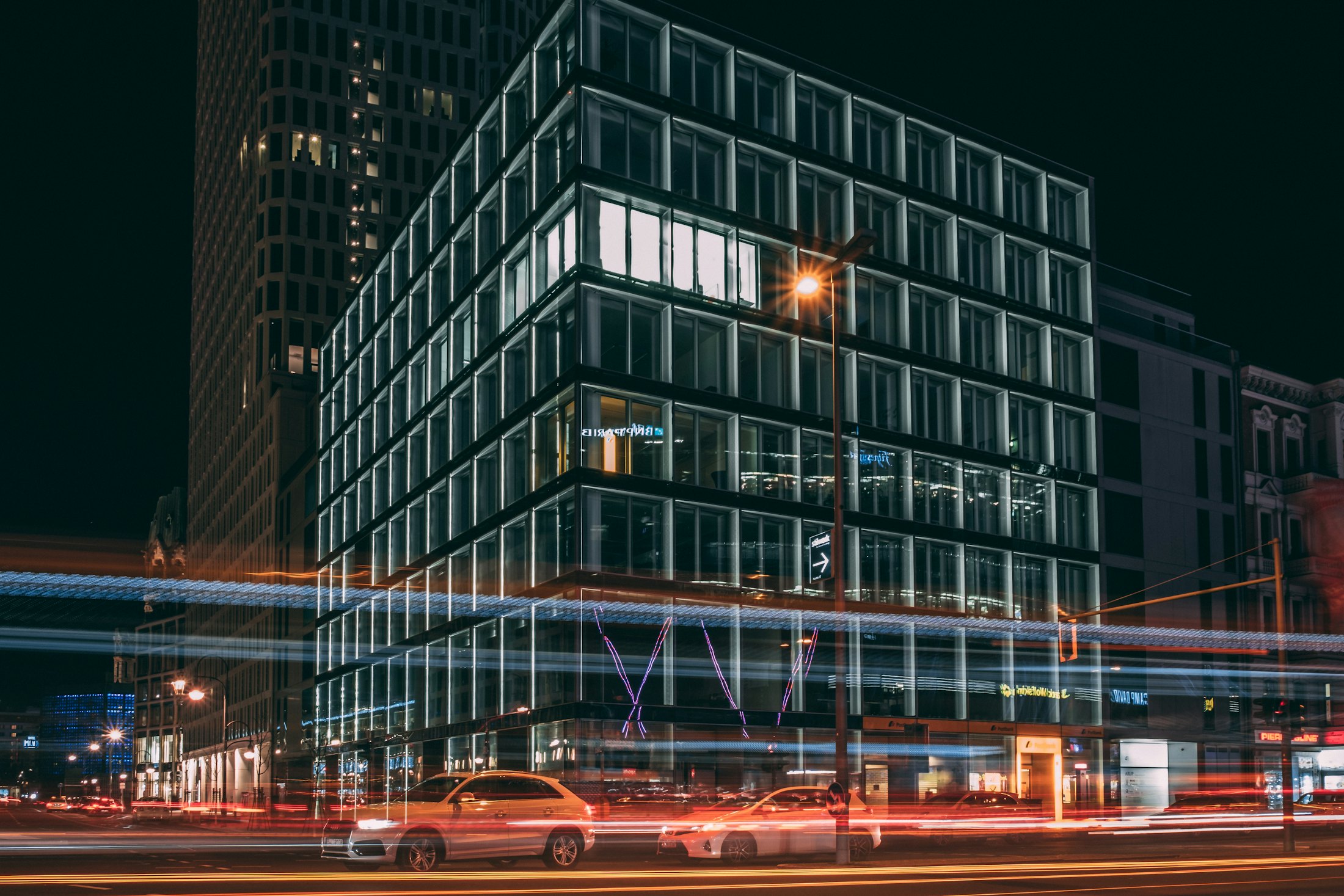 A lit office building at night with light trails from traffic